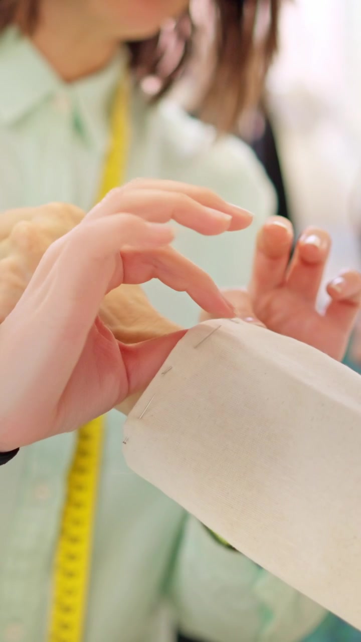Sarta che prova una giacca su un cliente in un laboratorio di cucito.