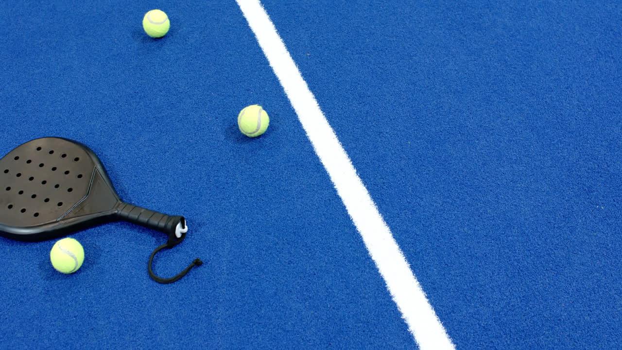 Padel racket and tennis balls on blue indoor court, ready for match