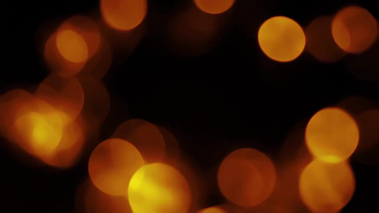 Luci bokeh arancioni calde che appaiono e si attenuano su sfondo nero