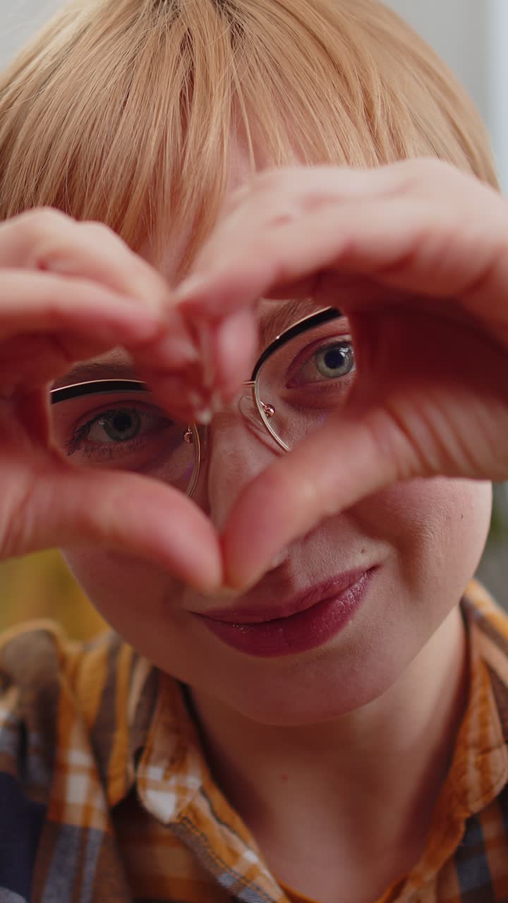 Mulher jovem e feliz faz um símbolo de amor mostrando um sinal de coração para a câmera, expressando sentimentos românticos