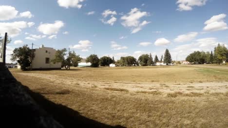lapso de tiempo - sentado en una cerca de madera mirando un campo vacío con hierba cortada mientras las nubes flotan en un día soleado