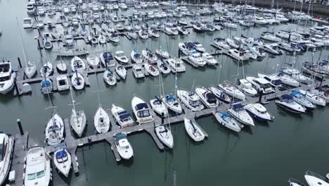 Aerial-view-rising-above-rows-of-luxury-wealthy-yachts-and-sailboats-moored-in-expensive-waterfront-marina