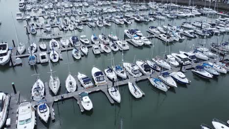 aerial view rising above rows of luxury wealthy yachts and sailboats moored in expensive waterfront marina