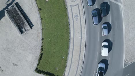 following the cars around about the marquis of pombal over a roundabout recording the historic sidewalk with some tourists visiting