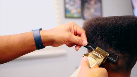 manos de peluquero cortando el cabello de un niño afroamericano irreconocible con una maquinilla de afeitar eléctrica