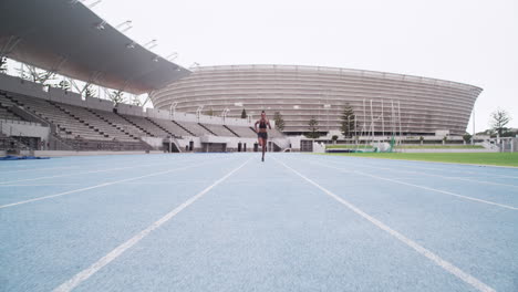 female athlete running on track in stadium