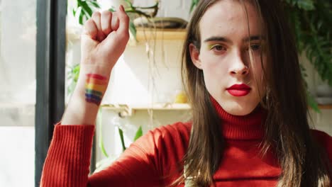 retrato de una mujer transgénero caucásica no binaria levantando la mano con la bandera lgbt
