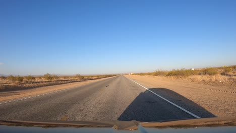 Driving-through-the-Mojave-Desert-on-a-dusty-and-lonely-road-at-sunset---driver-point-of-view