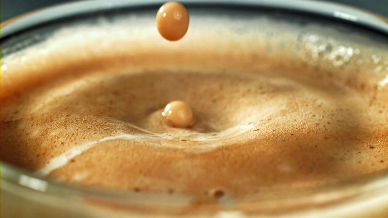 Goccia al rallentatore che si tuffa nel caffè con schiuma