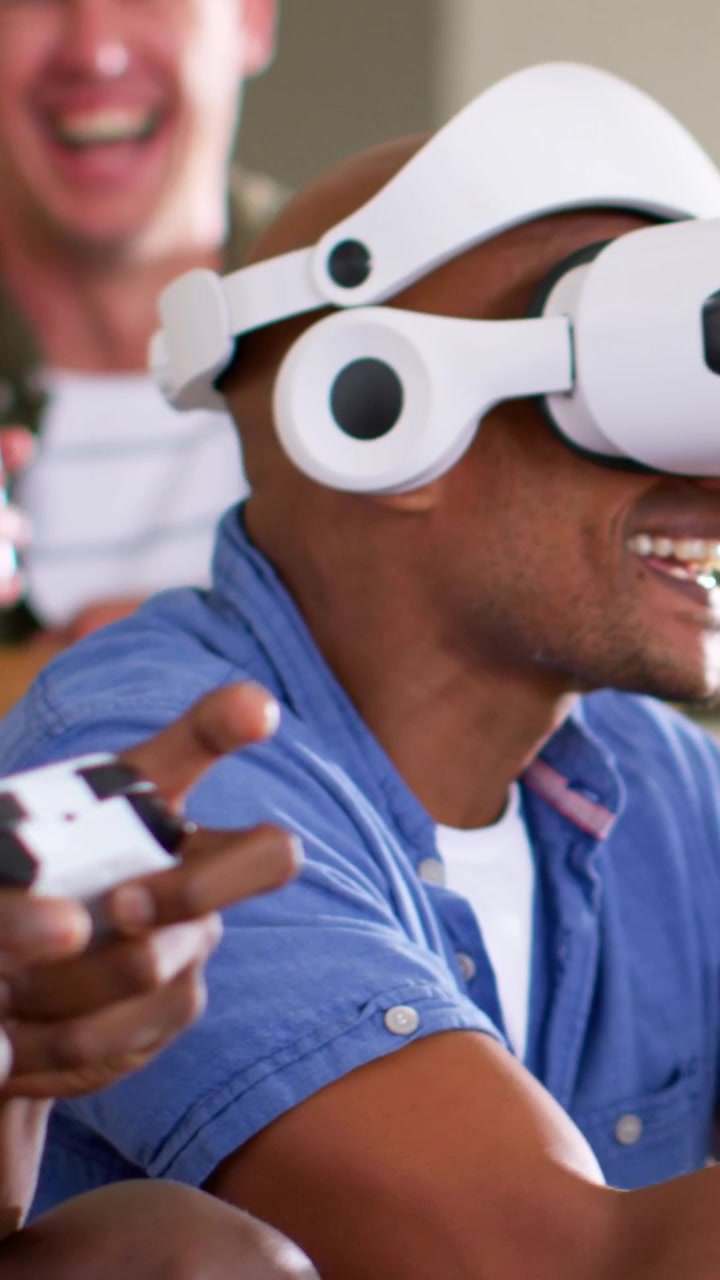 Vertical video: Putting headset on, man in red tee playing VR game at home with friends, copy space