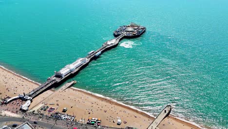 brighton comes alive under summer sun. vibrant beach scenes, shimmering sea, and jet skis dance around the iconic pier in this dynamic aerial view.