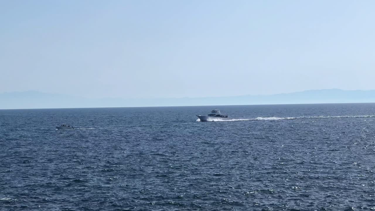 은 날 먼 산악 해안선과 함께 열린 바다를 가로질러 속도를 내는 보트