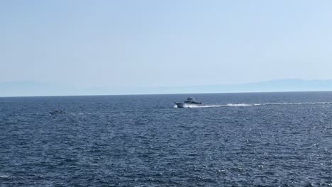 Barco-Acelerando-Sobre-Mar-Abierto-Con-Costa-Montañosa-Distante-En-Un-Día-Claro