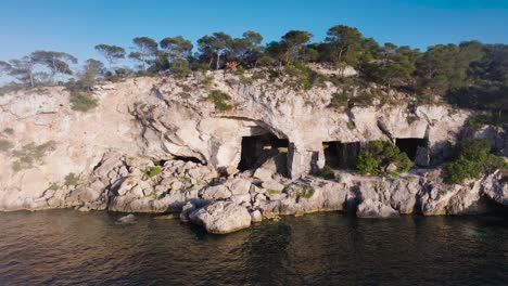 Flying-sideways-above-lagoon-near-old-Cova-de-Portals-Vells,-Mallorca