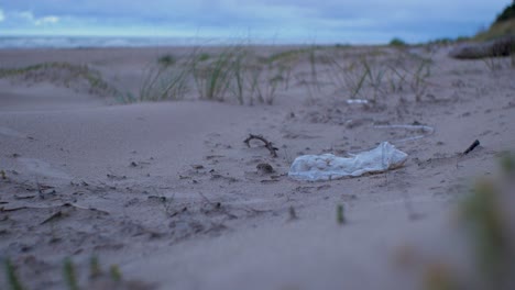 Bolsa-De-Plástico,-Basura-Y-Basura-En-Una-Playa-Vacía-De-Arena-Blanca-Del-Mar-Báltico,-Problema-De-Contaminación-Ambiental,-Noche-Nublada,-Tiro-Medio-Distante