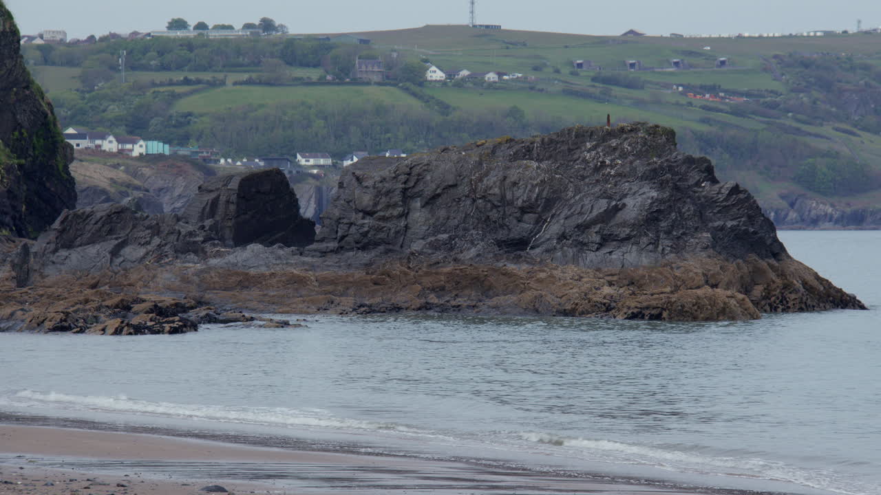 Vidvinkelbillede mod vest af blotlagte klipper ved lavvande på Tresaith Beach