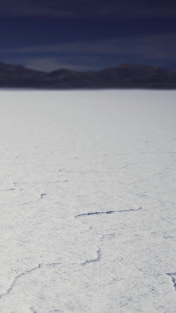 Winter landscape with cracked ice and distant mountains at midday