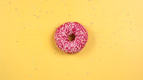 stop motion animation of donut rotate and got eaten. pink doughnut with white sprinkles on yellow background.colorful food animation. concept of tasty but unhealthy snack.