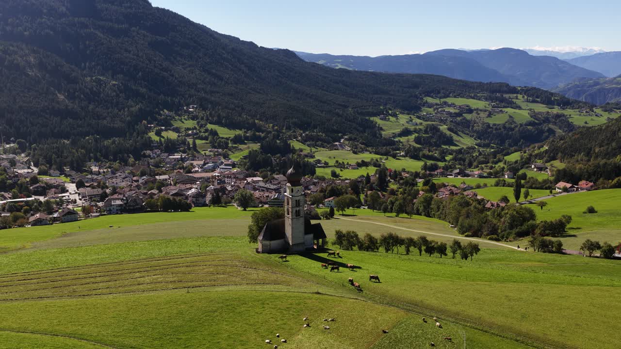Small church, chiesa in the Italian dolomites. Alpine fields, agricultural grass lands. Aerial video