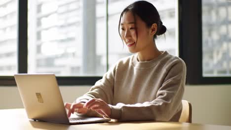a young woman engaged in work on a laptop in a bright, modern environment, reflecting focus, productivity, and innovation in daily life