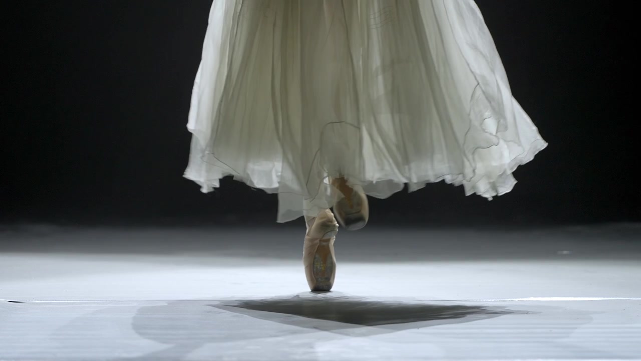 Ballerina Dancing on Pointe in White Tutu on Stage