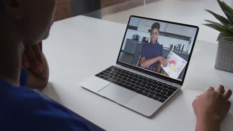 Mid-section-of-african-american-woman-having-a-video-call-on-laptop-with-female-colleague-at-office