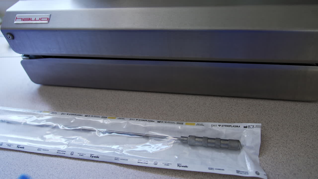 Hand of medic in latex gloves put the bag with instrument on the table. Preparation of tool for vacuum packaging in equipment.