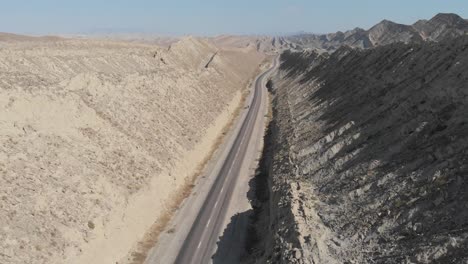 Vuelo-Aéreo-Sobre-La-Carretera-Costera-Vacía-De-Makran-Junto-A-Espectaculares-Formaciones-Rocosas-En-El-Parque-Nacional-Hingol