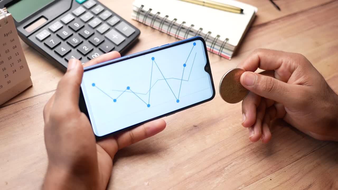 persona con bitcoin y mirando la ficha telefónica