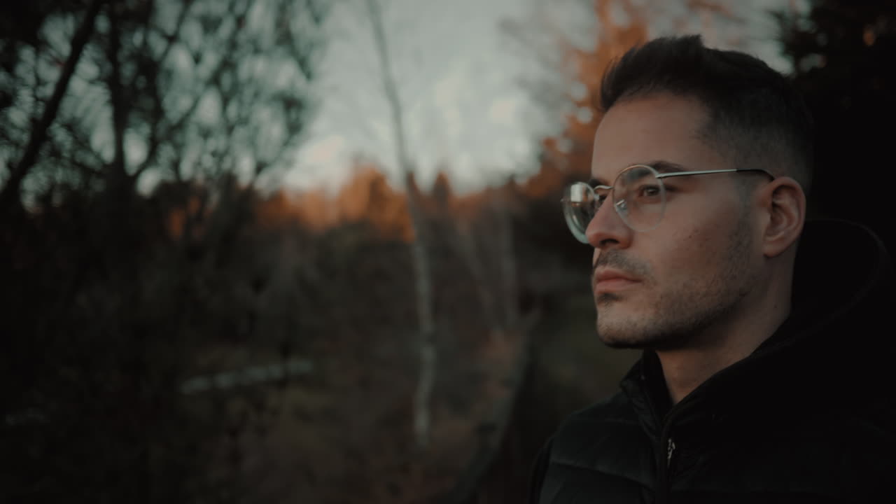 foto reveladora de un blogger de viajes o fotógrafo parado cerca de una cerca en la naturaleza sosteniendo una cámara dslr y mirando el horizonte para analizar la mejor composición para una fotografía de paisaje