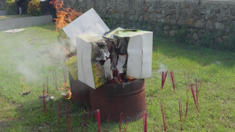 burning incense paper during cheng beng or qingming, chinese festival, to honor deceased ancestors