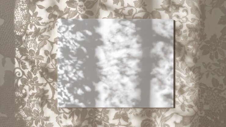 Sunlight through leaves casting drifting dappled light across white card on floral cloth