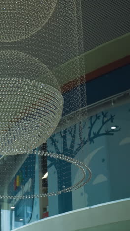 view of elegant chandeliers in a modern building interior, featuring both large and small chandeliers hanging from the ceiling. captured with a handheld camera