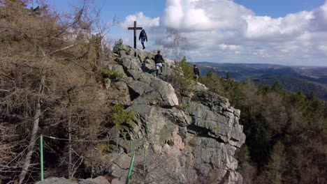 aerial view flying past hikers climbing rocky path to view wide open landscape and lake at sunset