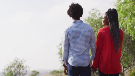 Happy-african-american-couple-walking-together-and-holding-hands-on-sunny-day,-slow-motion