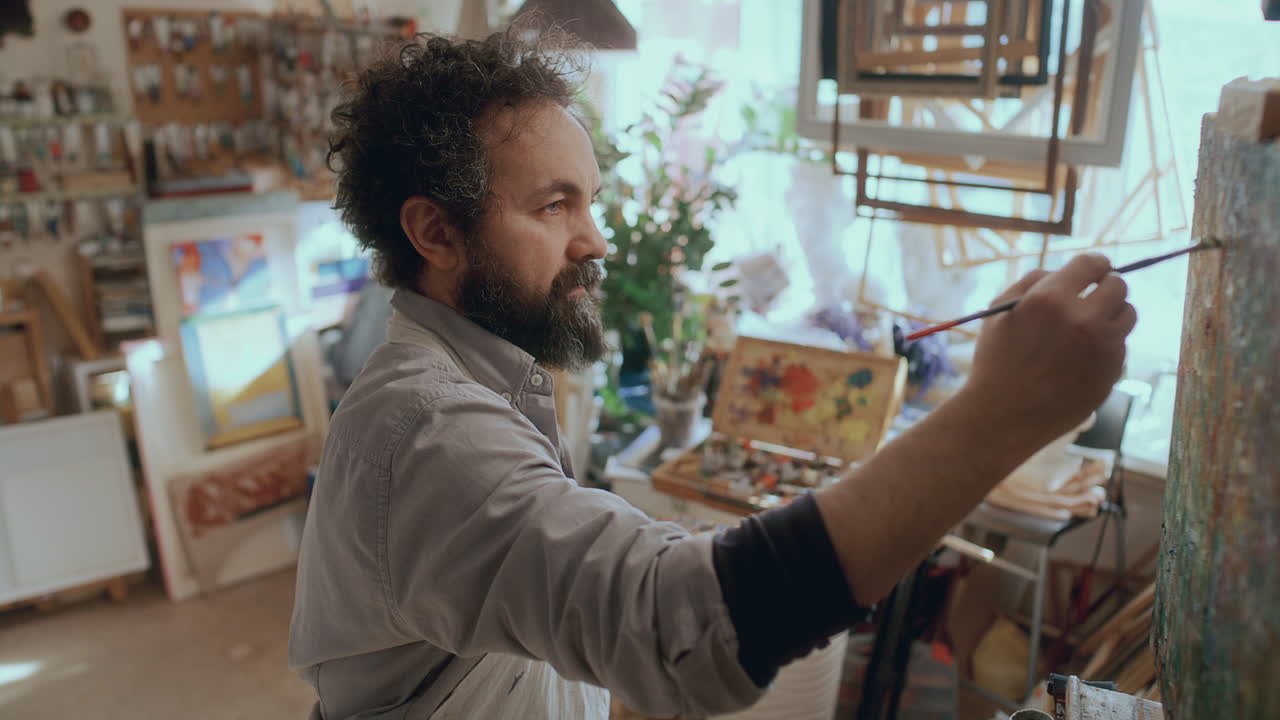 Kunstner blander farver på palet og maler på lærred i kreativt studie