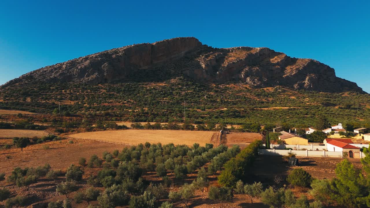 Valle rurale con un piccolo villaggio sotto una montagna rocciosa