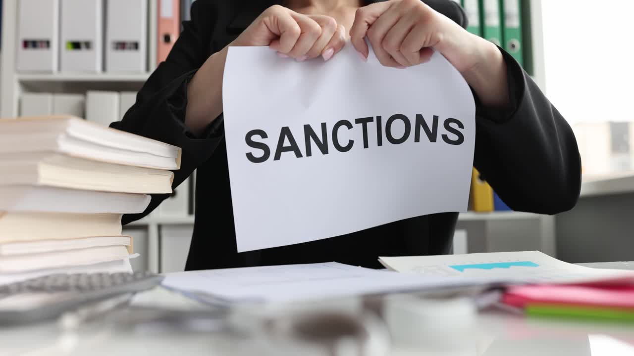 Woman tearing up a paper with the word "Sanctions"