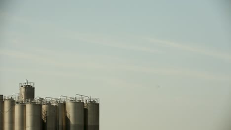 Silos-Vor-Einem-Blassen-Himmel-Im-Morgengrauen,-Subtiler-Industrieller-Charme-Mit-Sanfter-Natürlicher-Beleuchtung