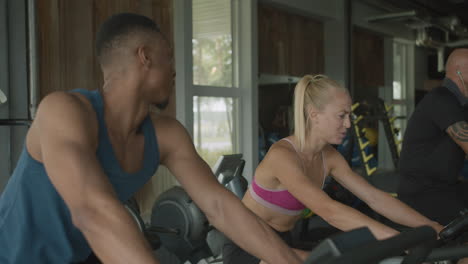 side view of caucasian female monitor and an athletic african american man in the gym.