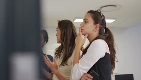 grupo diverso de compañeras de trabajo brainstorming de pie junto a una pared de vidrio