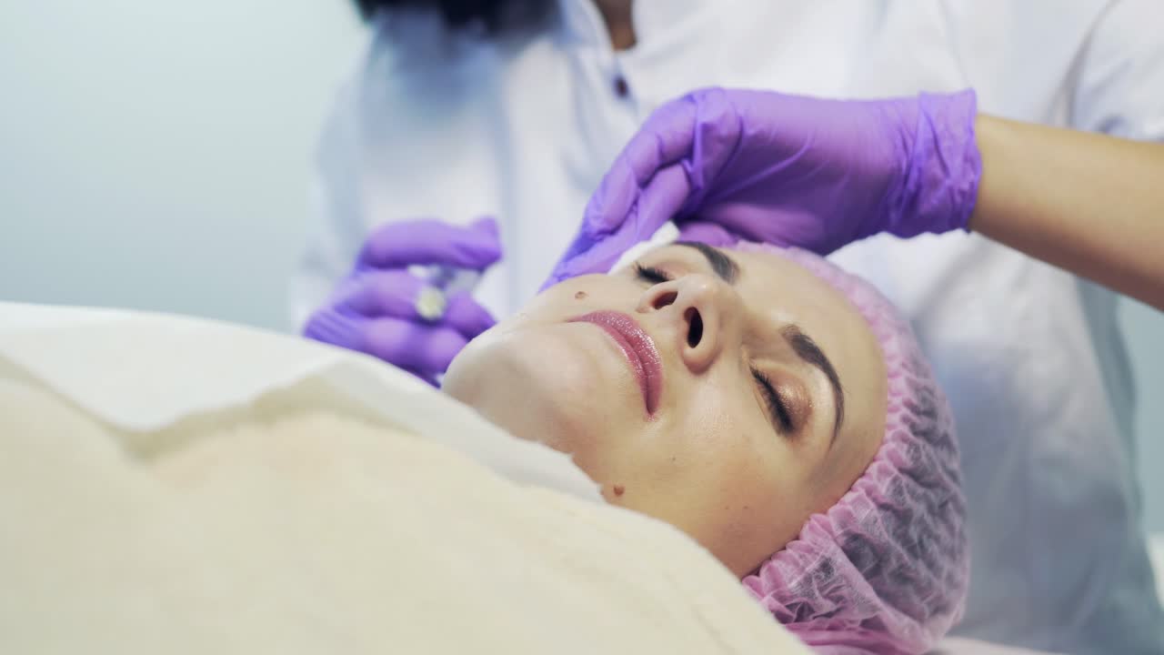 Professional cosmetologist making facial injection in spa. Portrait of a female during surgery filling facial wrinkles
