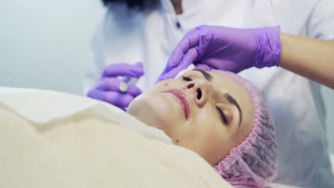 professional cosmetologist making facial injection in spa. portrait of a female during surgery filling facial wrinkles