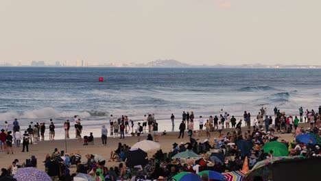 busy beach scene with people and city skyline