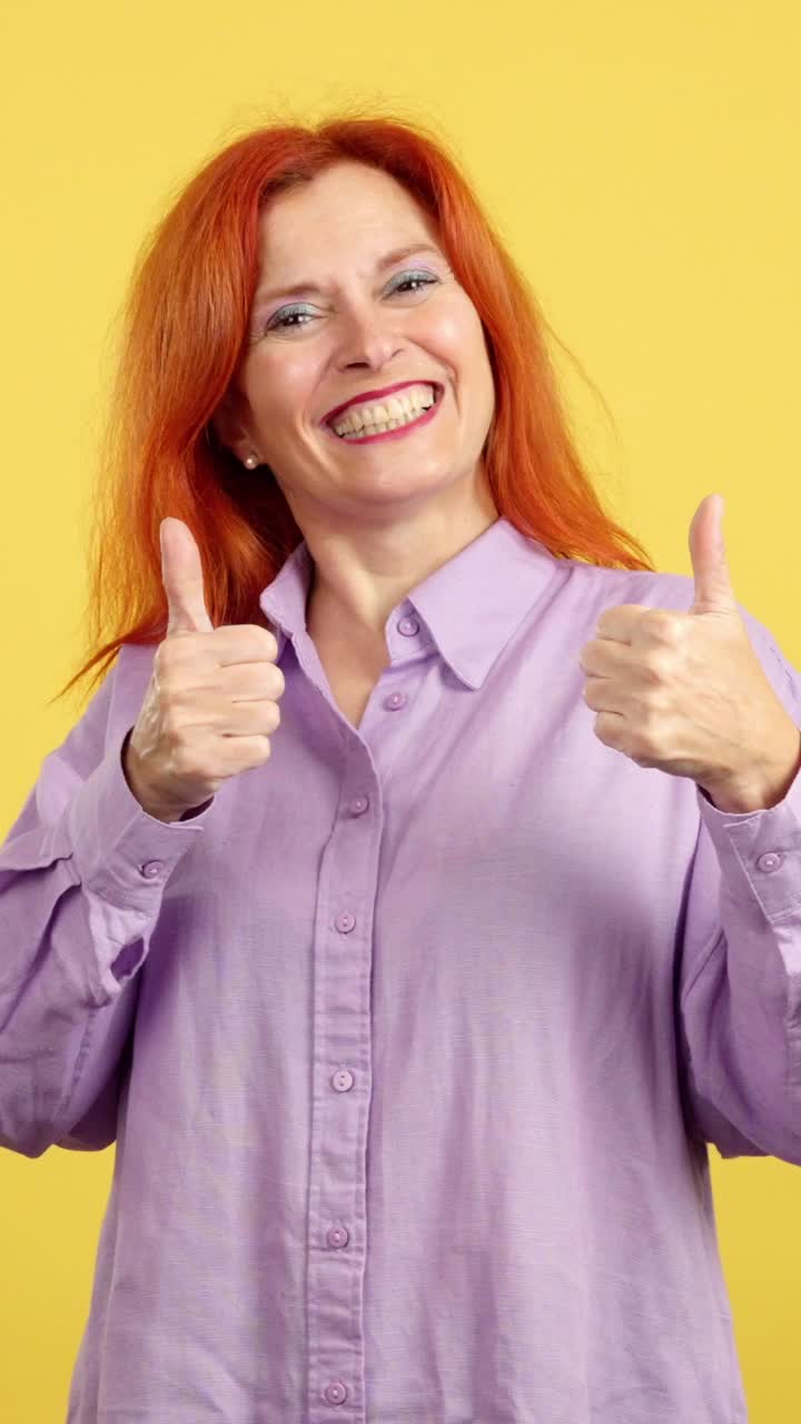 Happy Woman Giving Thumbs Up Against a Yellow Background
