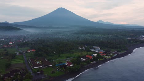 imágenes aéreas del pueblo de pescadores de amed al amanecer con niebla sobre la palmera de la jungla y el volcán activo monte agung