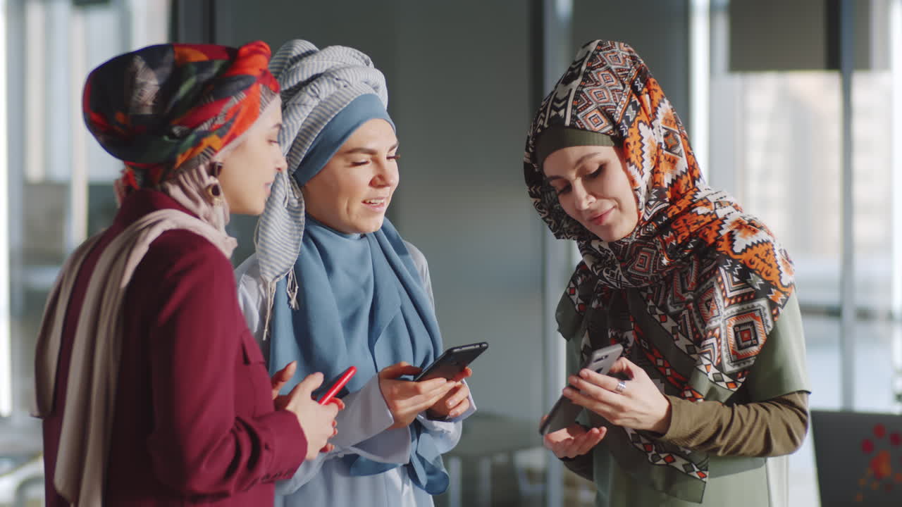 스마트폰을 사용하고 채팅하는 무슬림 여성 동료들