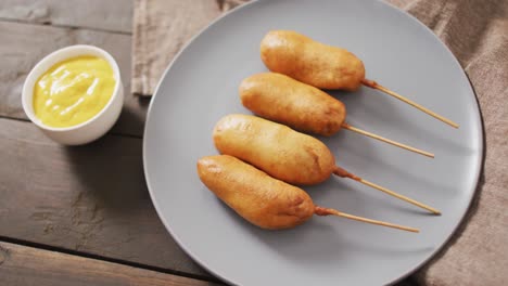 video of corn dogs with dips on a wooden surface