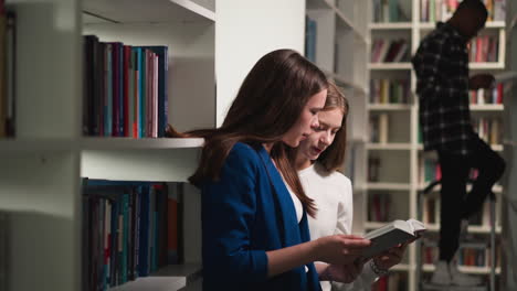 las mujeres jóvenes tienen un libro en la biblioteca pública. los lectores encuentran literatura interesante contra el hombre negro en la escalera en la librería. archivo universitario