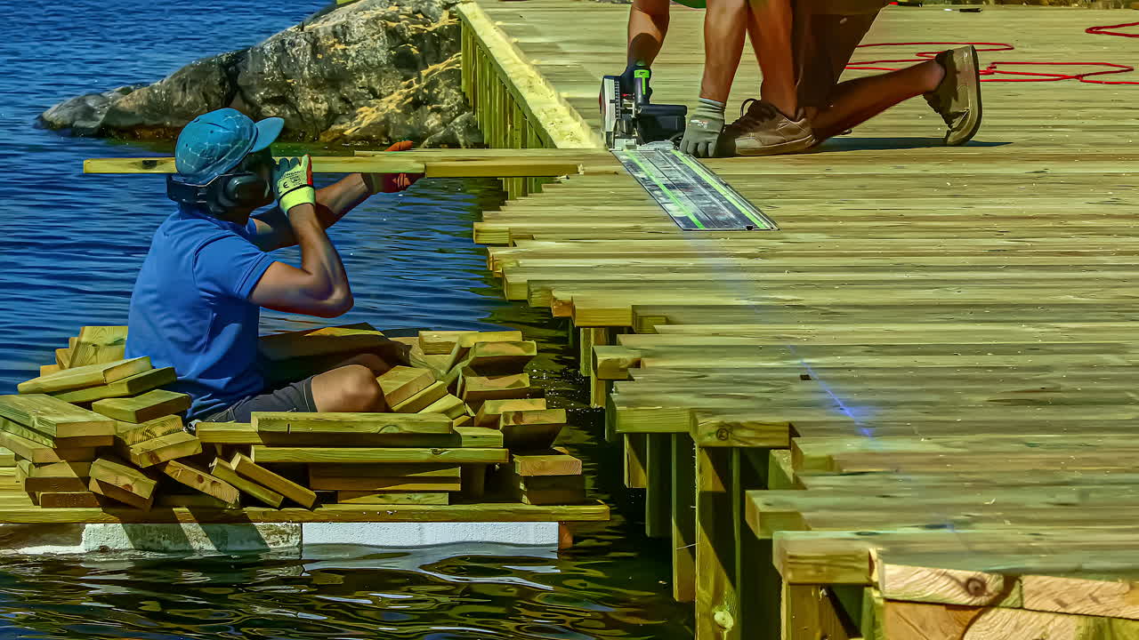 Time lapse shot of worker repairing wooden jetty of sea during sunny day in Stockholm,Sweden - Man Sitting on wooden boat and working